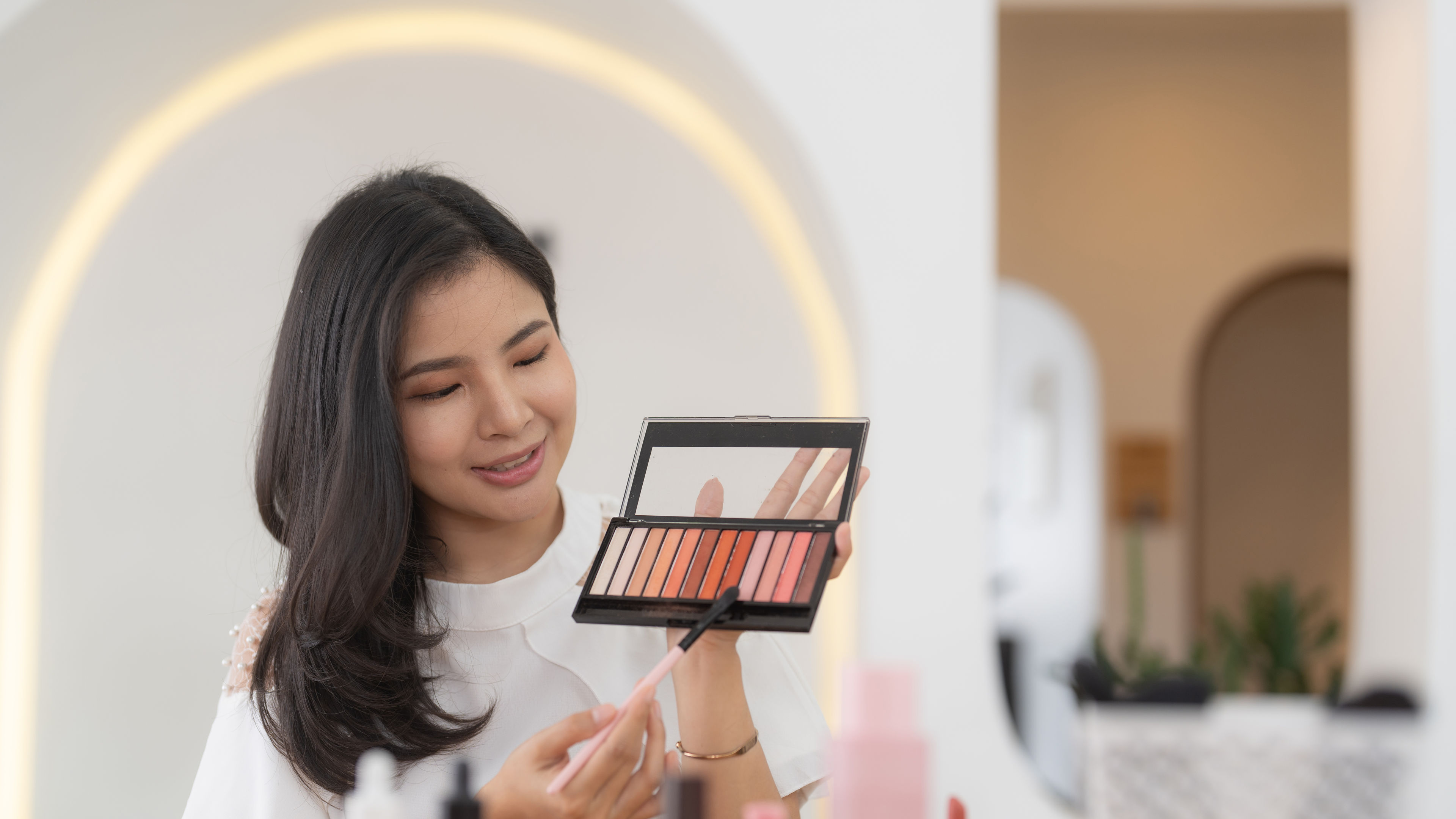 Asian female beauty blogger live streaming to review makeup product on social media
