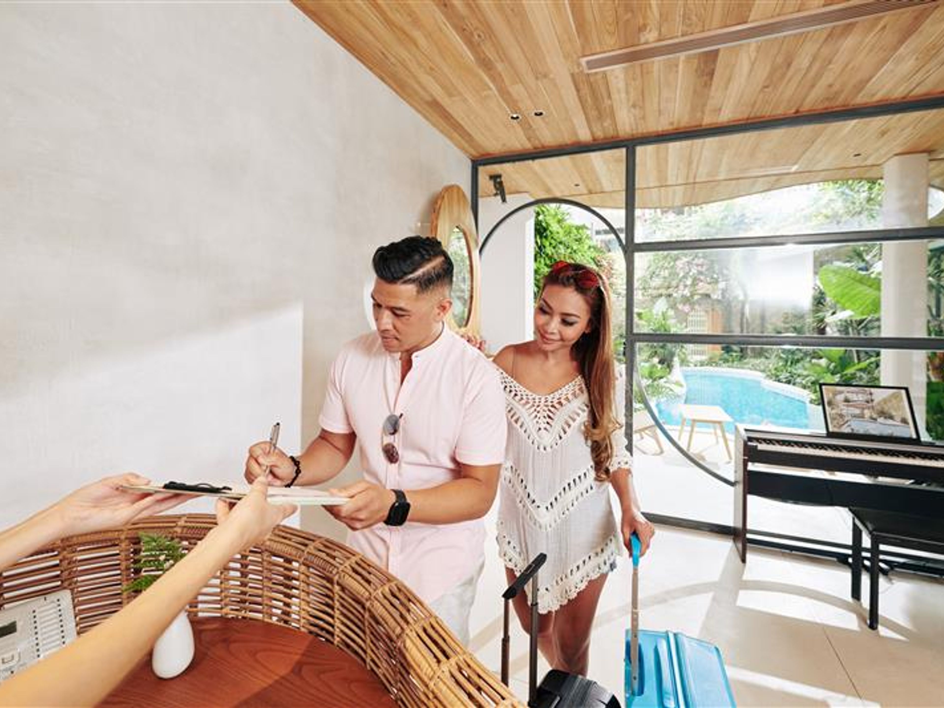 Man filling document for him and his wife when standing at reception of spa hotel. 
